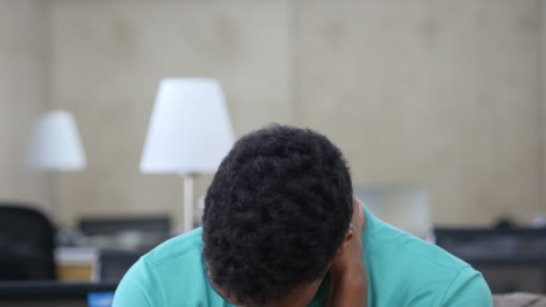 Уставший черный молодой человек в офисе, портрет — стоковое видео