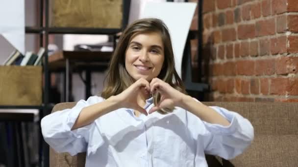 Hjärta form med händer av unga vackra flicka sitter på soffa — Stockvideo