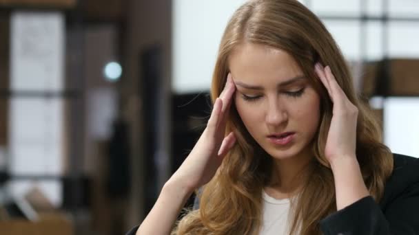 Dolor de cabeza, frustrado, trastornado, chica tensa sentada en interiores — Vídeos de Stock