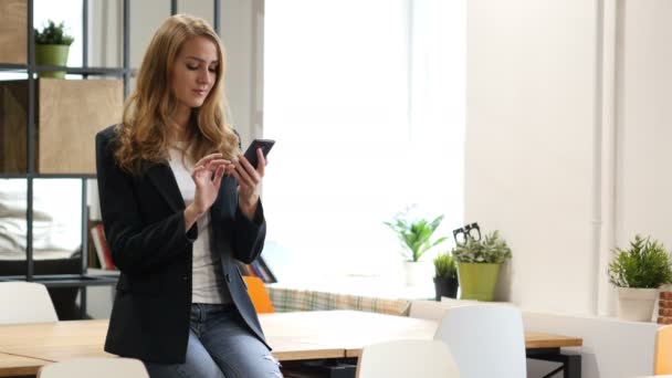 Surfar på nätet på Smartphone av affärskvinna som sitter på skrivbord — Stockvideo