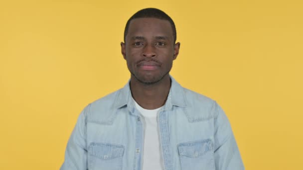 Hombre joven africano mirando a la cámara, fondo amarillo — Vídeo de stock