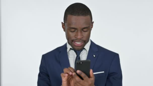Afrikaanse zakenman juichen succes op Smartphone, Witte achtergrond — Stockvideo