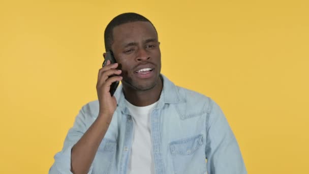 Giovane uomo africano che parla su smartphone, sfondo giallo — Video Stock