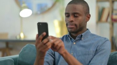 Evde akıllı telefon kullanan genç bir Afrikalı. 