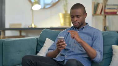 Kanepede akıllı telefon kullanan ciddi bir Afrikalı. 