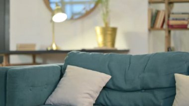 Dizüstü bilgisayarlı genç Afrikalı adam geri geliyor, koltukta oturuyor. 