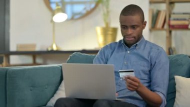 Kanepede Genç Afrikalı Adam tarafından dizüstü bilgisayarda online alışveriş başarısı
