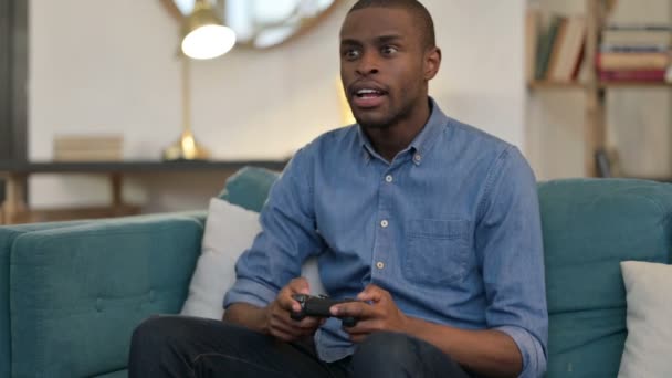 Fiatal afrikai férfi, amelynek elvesztése videojáték kanapén — Stock videók