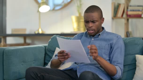 Young African Man with Documents reacting to Loss on Sofa — Stock Video