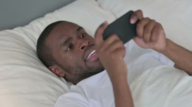 Afrikalı Adam Yatakta Akıllı Telefonla Oyun Oynuyor