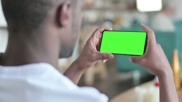 Hombre joven africano mirando Smartphone con pantalla de croma verde — Vídeo de stock