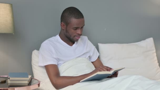 Young African Man Reading Könyv az ágyban — Stock videók