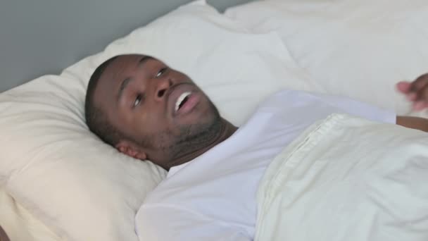 Jonge Afrikaanse man wakker uit nachtmerrie in bed — Stockvideo