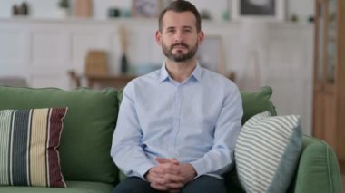 Mutlu genç adam koltukta oturup düşünüyor. 