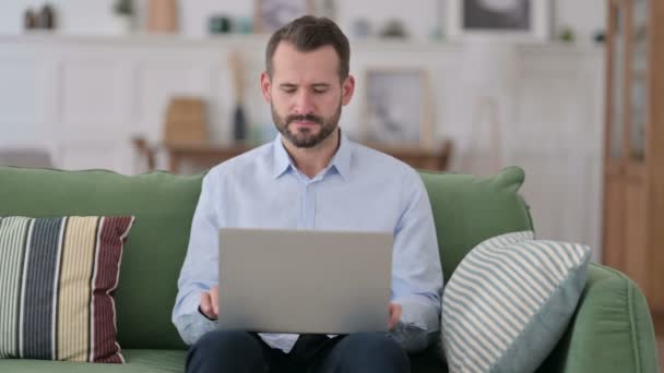 Pensive Young Man with Laptop Thinking on Sofa — Stock Video