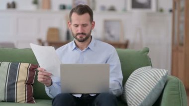 Evdeki Belgeler ve Laptop Üzerinde Çalışan Genç Adam