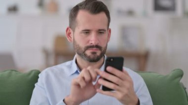 Genç adam evde akıllı telefondan kutlama yapıyor. 