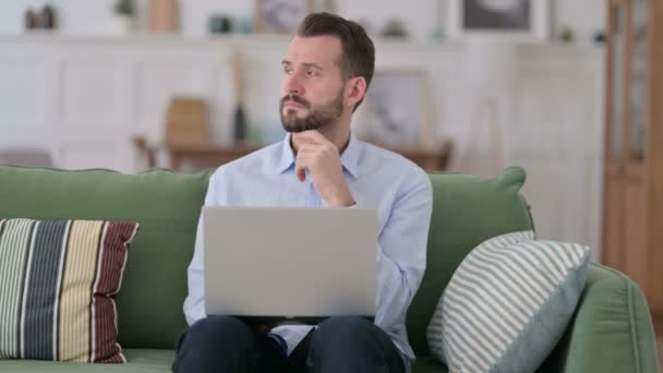 Jovem Pensivo com Laptop Pensando no Sofá — Vídeo de Stock