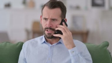 Kızgın genç adam telefonda konuşuyor.