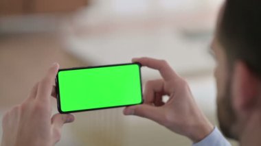 Yeşil Krom Ekran ile Akıllı Telefon İzleyen Genç Adam 