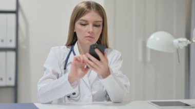Genç bayan doktor iş yerinde akıllı telefon kullanıyor. 