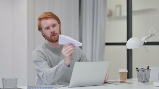 Rotschopf mit Laptop versucht Papierflugzeug zu fliegen — Stockvideo