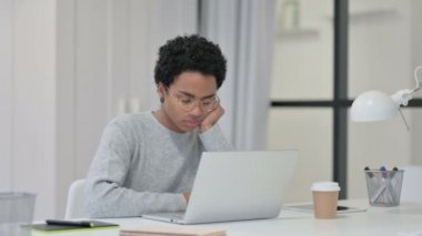 Dizüstü bilgisayarı olan genç Afrikalı kadın iş yerinde kestiriyor 