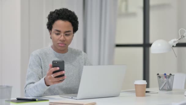 Mulher Africana com Laptop usando Smartphone no trabalho — Vídeo de Stock