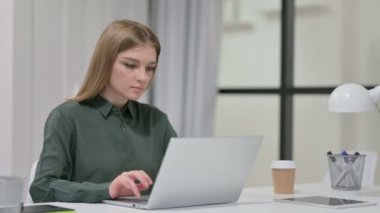 Ofisteki dizüstü bilgisayarda çalışan genç kadın. 