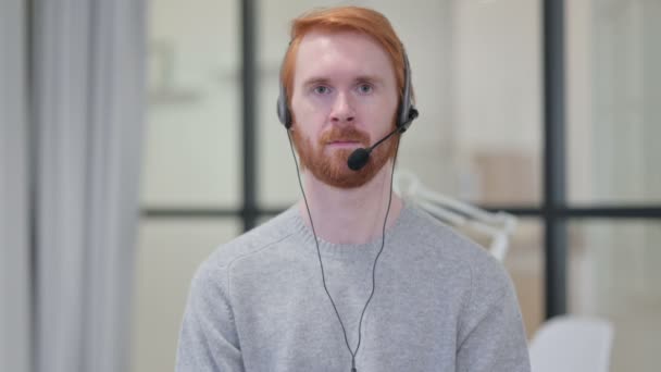 Portret uśmiechniętego rudego mężczyzny noszącego słuchawki z mikrofonem — Wideo stockowe