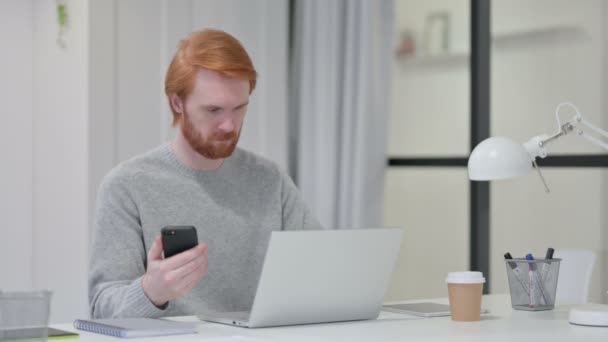 Rotschopf mit Laptop und Smartphone bei der Arbeit — Stockvideo