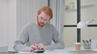 Kağıt üzerine yazarken Kızıl Adam Hesap Makinesi kullanıyor 