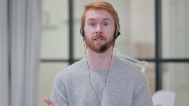 Retrato del hombre pelirrojo hablando a través de auriculares con micrófono — Vídeos de Stock