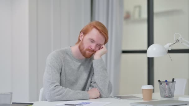 Sömnig ung rödhårig man som tar en tupplur på jobbet — Stockvideo