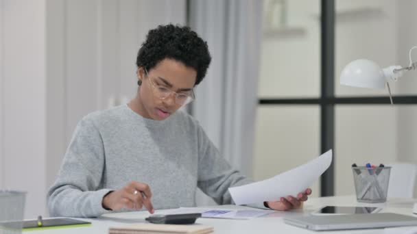 African Woman using Calculator while Writing on Paper — Stock Video