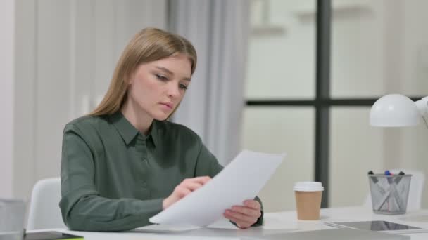 Молода жінка читає документи на роботі — стокове відео
