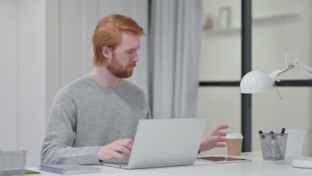 Rotschopf trinkt Kaffee, während er am Laptop tippt — Stockvideo