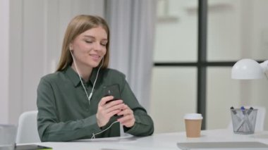 İş yerinde Smartphone 'da Müzik Dinleyen Genç Kadın 