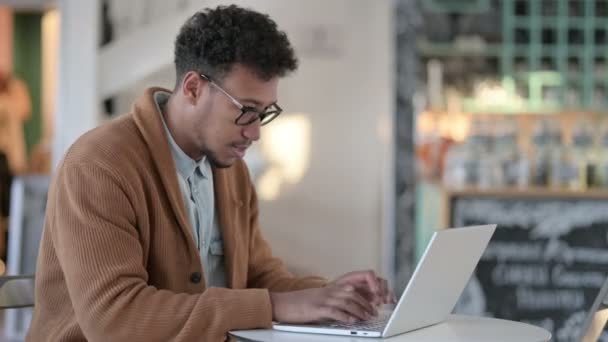 Erfolgreicher Afrikaner feiert auf Laptop im Café — Stockvideo