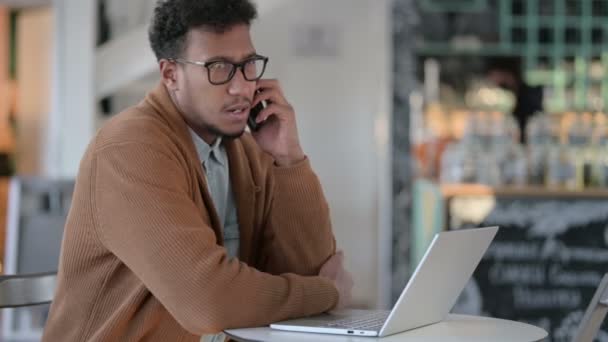 Uomo africano con computer portatile Parlare su Smartphone — Video Stock