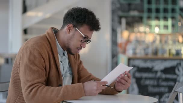 Happy African Man Reading Papers в кафе — стоковое видео