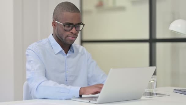 Homem africano deixando o escritório após o trabalho, fechando o portátil — Vídeo de Stock