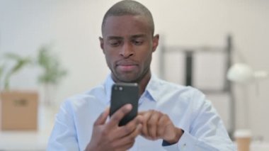 Ofiste akıllı telefon kullanan Afrikalı adam