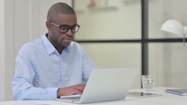 Hombre africano trabajando en el ordenador portátil en la oficina — Vídeo de stock