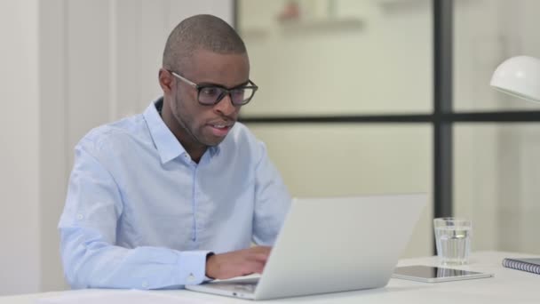 Hombre africano tosiendo mientras trabaja en el ordenador portátil — Vídeo de stock