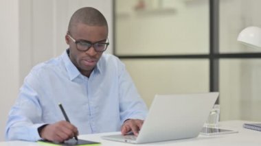 Dizüstü bilgisayar ve grafik tableti kullanarak Tasarım Oluşturan Afrikalı Tasarımcı