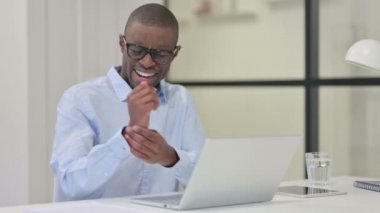 Dizüstü bilgisayarda yazarken bileği ağrıyan Afrikalı bir adam 