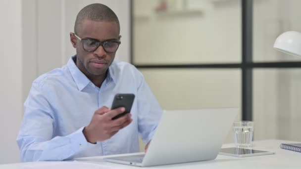 Hombre africano usando Smartphone y Laptop para el trabajo — Vídeo de stock
