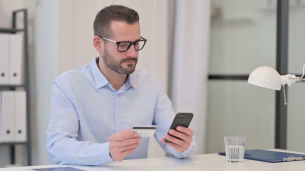 Hombre de mediana edad Emocionado por el éxito de compras en línea en el teléfono inteligente — Vídeo de stock