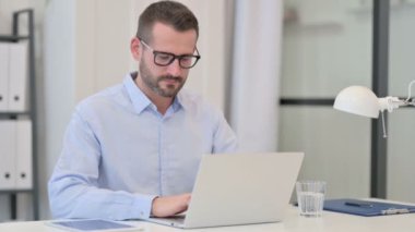 Bilgisayarlı orta yaşlı adam Kameraya bakıyor 